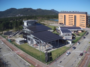 Vista aérea do espaço fotovoltaico da UFSC em Florianópolis, com sistemas de energia solar instalados para pesquisa e formação técnica.